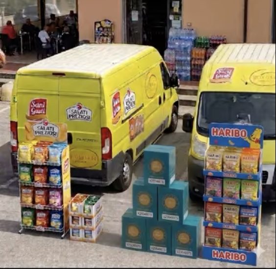 Due furgoni Secolo Commerciale in consegna davanti a un bar, con espositori Haribo e Salati Preziosi